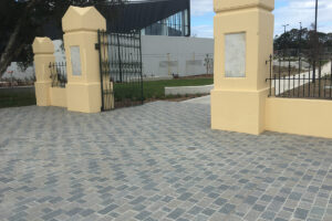 Porphyry two colour mix cobblestones laid in a driveway with grey and beige tones outside a gated property entrance