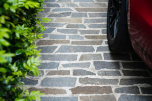 Italian Filetti stone paving on a driveway beside a red car, featured in Top Deck Landscapes’ top outdoor design trends of 2023